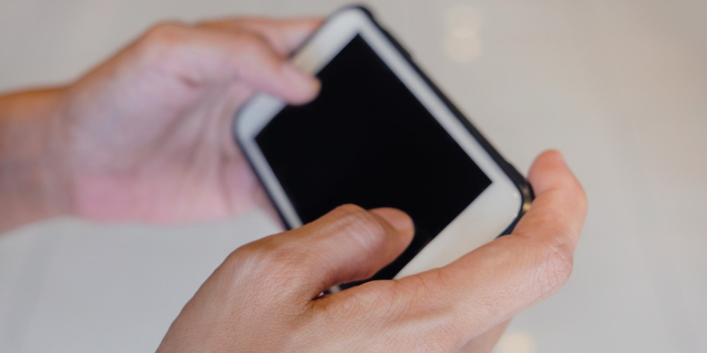 A guy plays with both hands on his iPhone